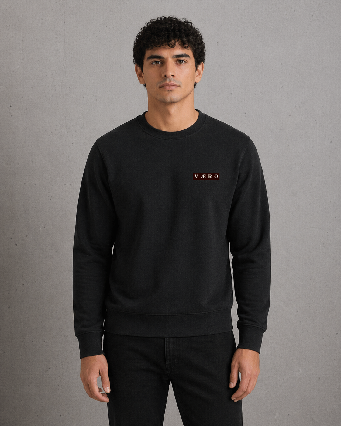 Man wearing a black sweatshirt with a logo on a gray background