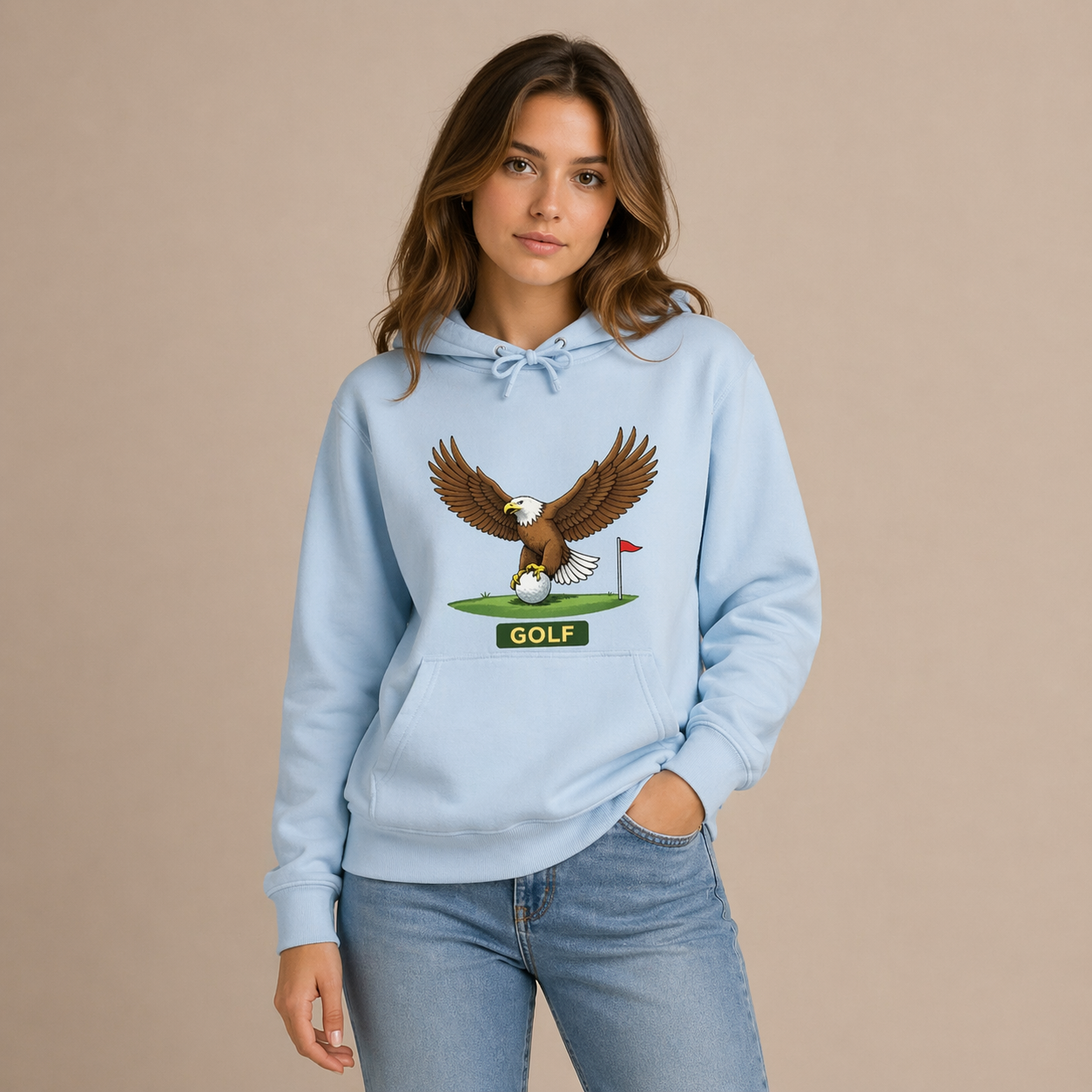 Woman wearing a light blue hoodie with an eagle and golf design on a beige background