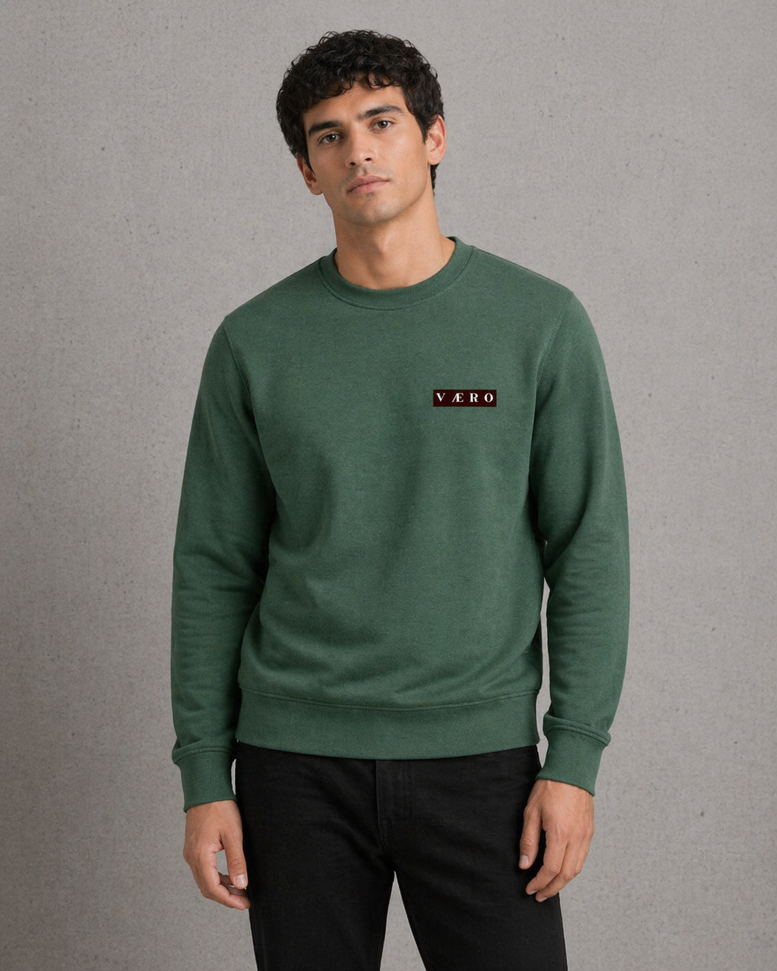 Man wearing a green sweatshirt with a logo on a gray background