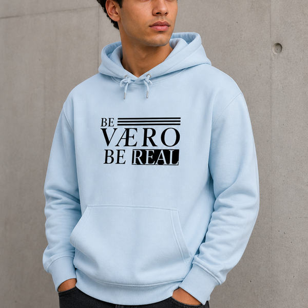 Person wearing a light blue hoodie with text design against a concrete wall.