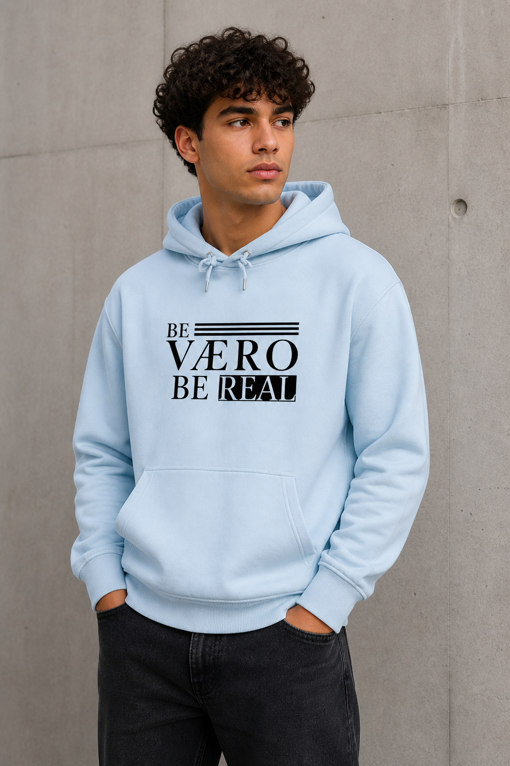 Person wearing a light blue hoodie with text design against a concrete wall.