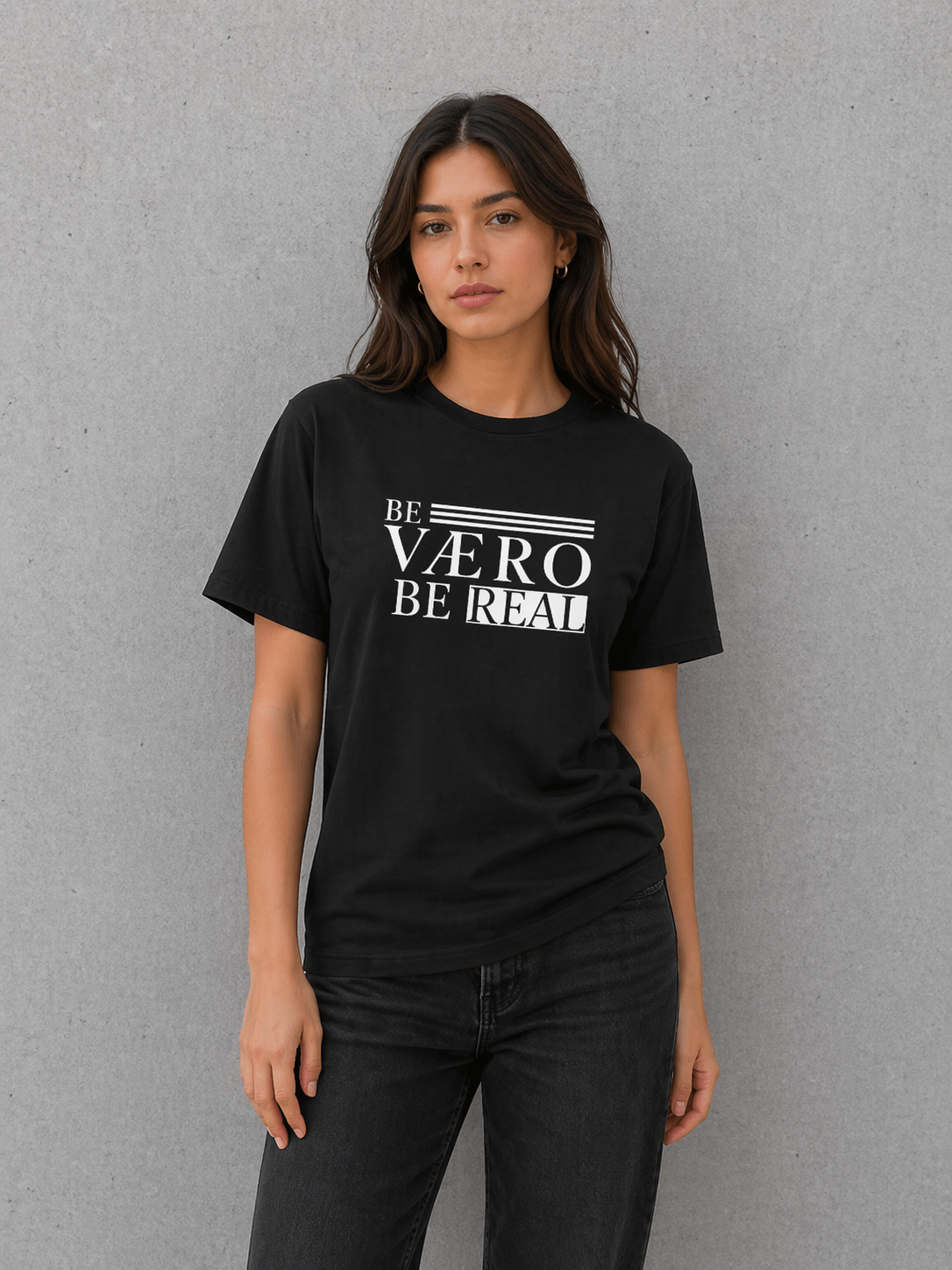 Woman wearing a black t-shirt with 'BE VAERO BE REAL' text on a gray background
