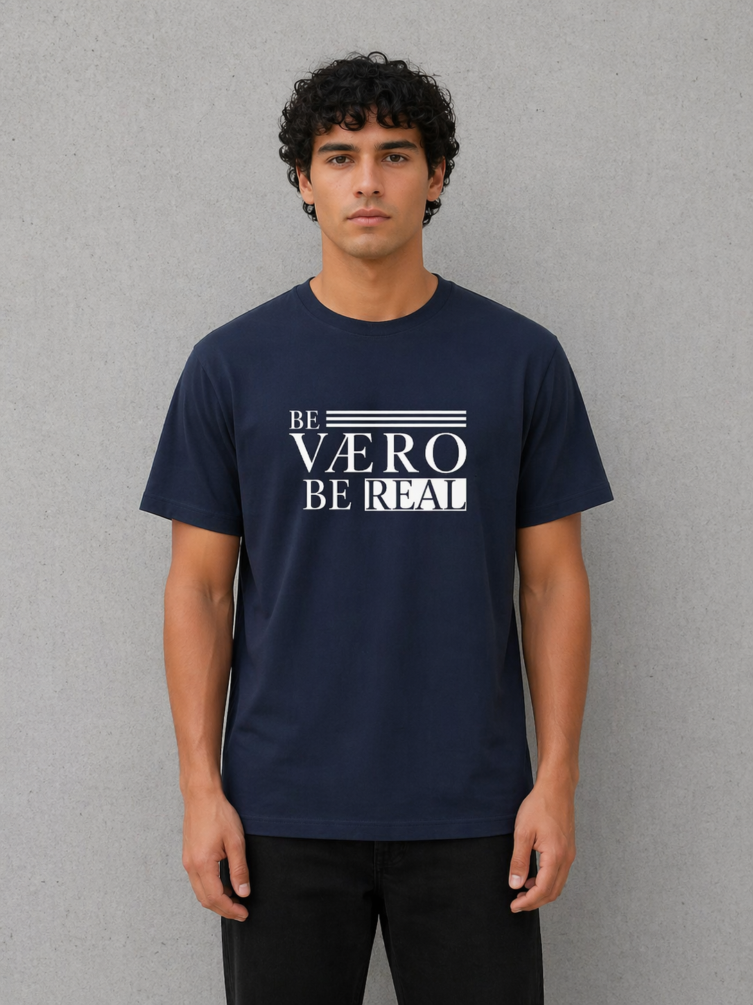 Man wearing a navy blue t-shirt with 'BE VAERO BE REAL' text on a gray background