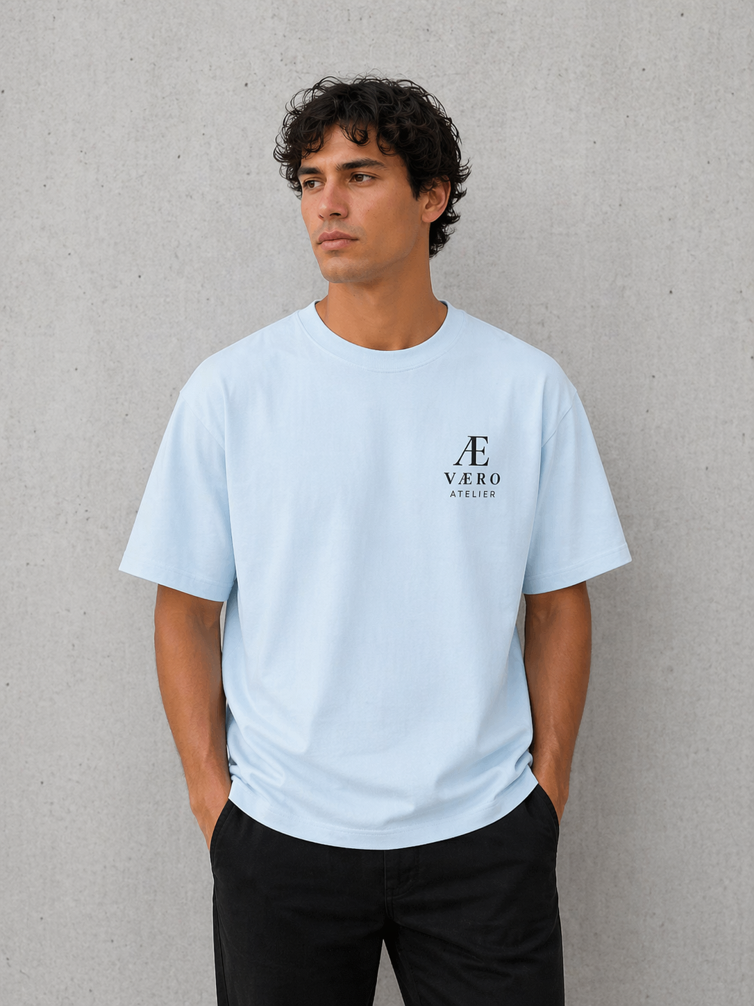 Man wearing a light blue t-shirt with a logo against a gray background