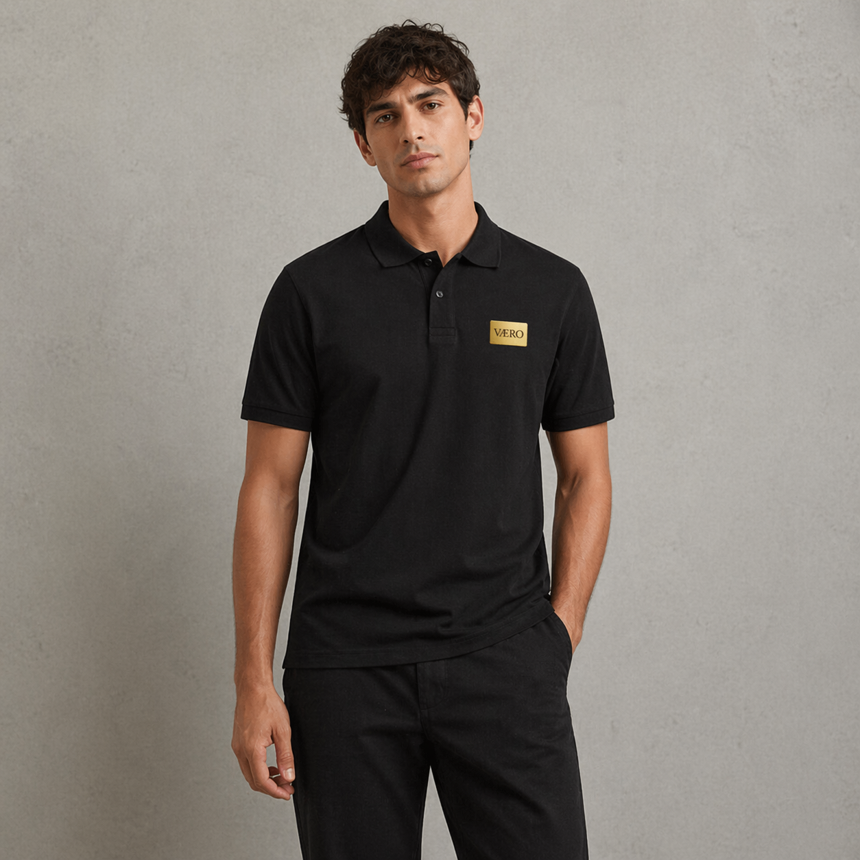 Man wearing a black polo shirt with a logo on a gray background