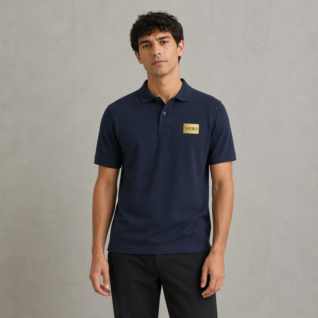 Man wearing a navy blue polo shirt with a logo on a gray background