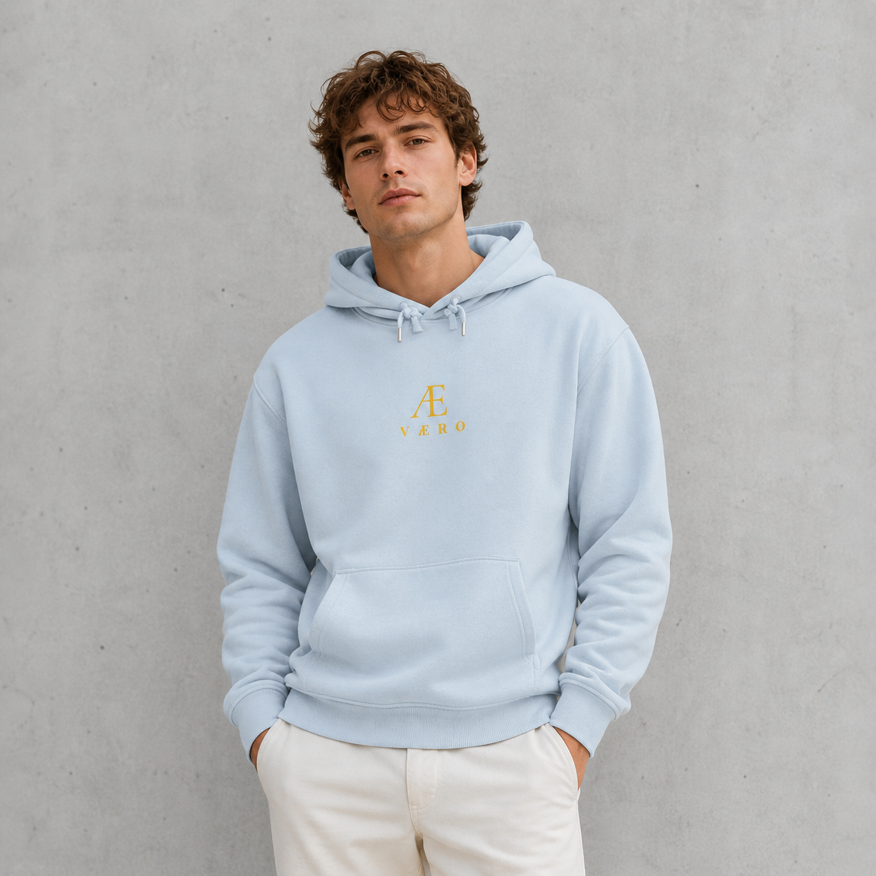 Person wearing a light blue hoodie with a logo on a gray background
