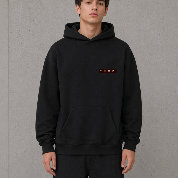 Person wearing a black hoodie with a logo on a gray background