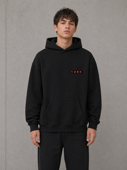 Person wearing a black hoodie with a logo on a gray background