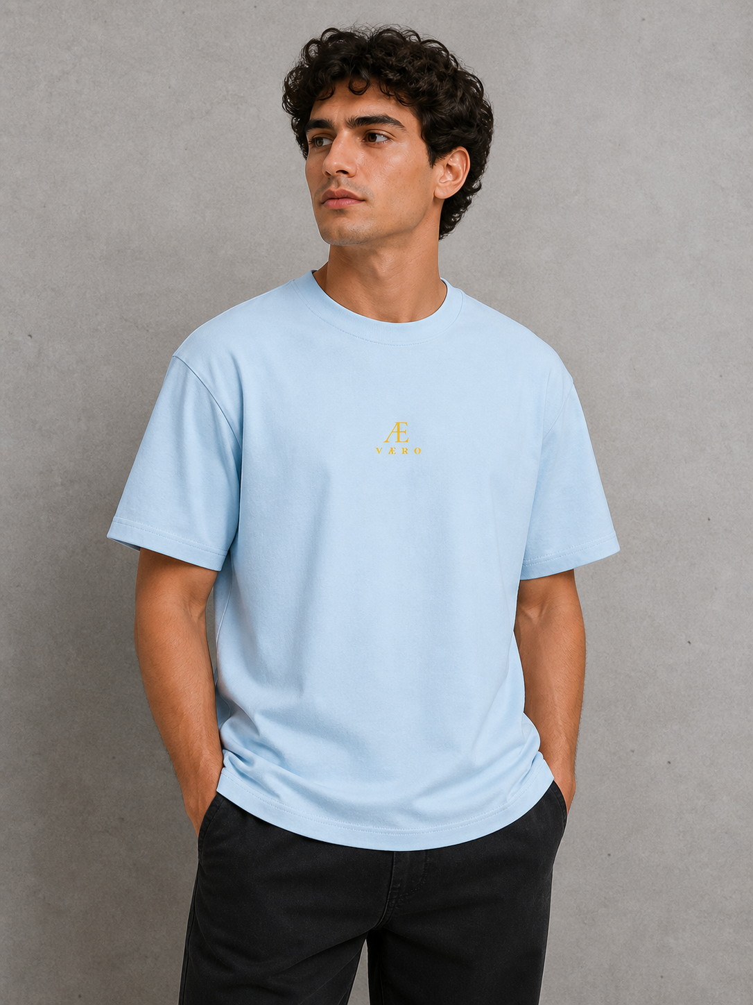 Man wearing a light blue t-shirt with a logo against a gray background