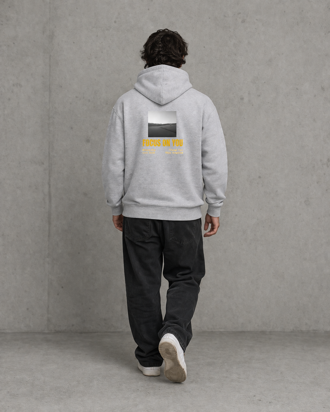 Person wearing a gray hoodie with a graphic on the back against a plain background