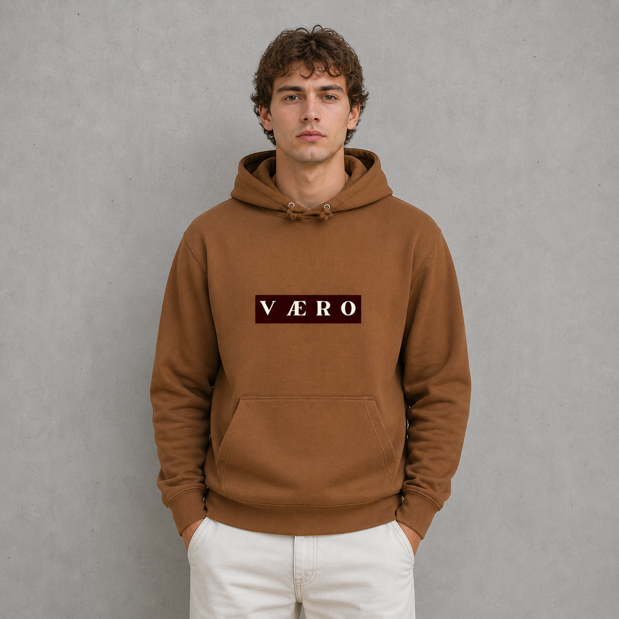 Man wearing a brown hoodie with 'VAERO' logo against a gray background