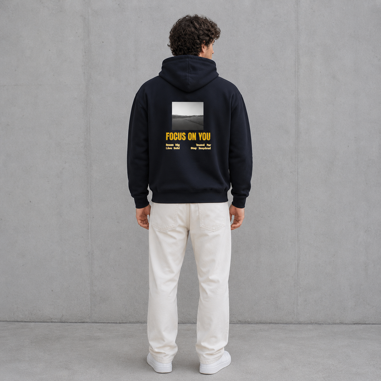 Person wearing a black hoodie with text on the back against a gray background