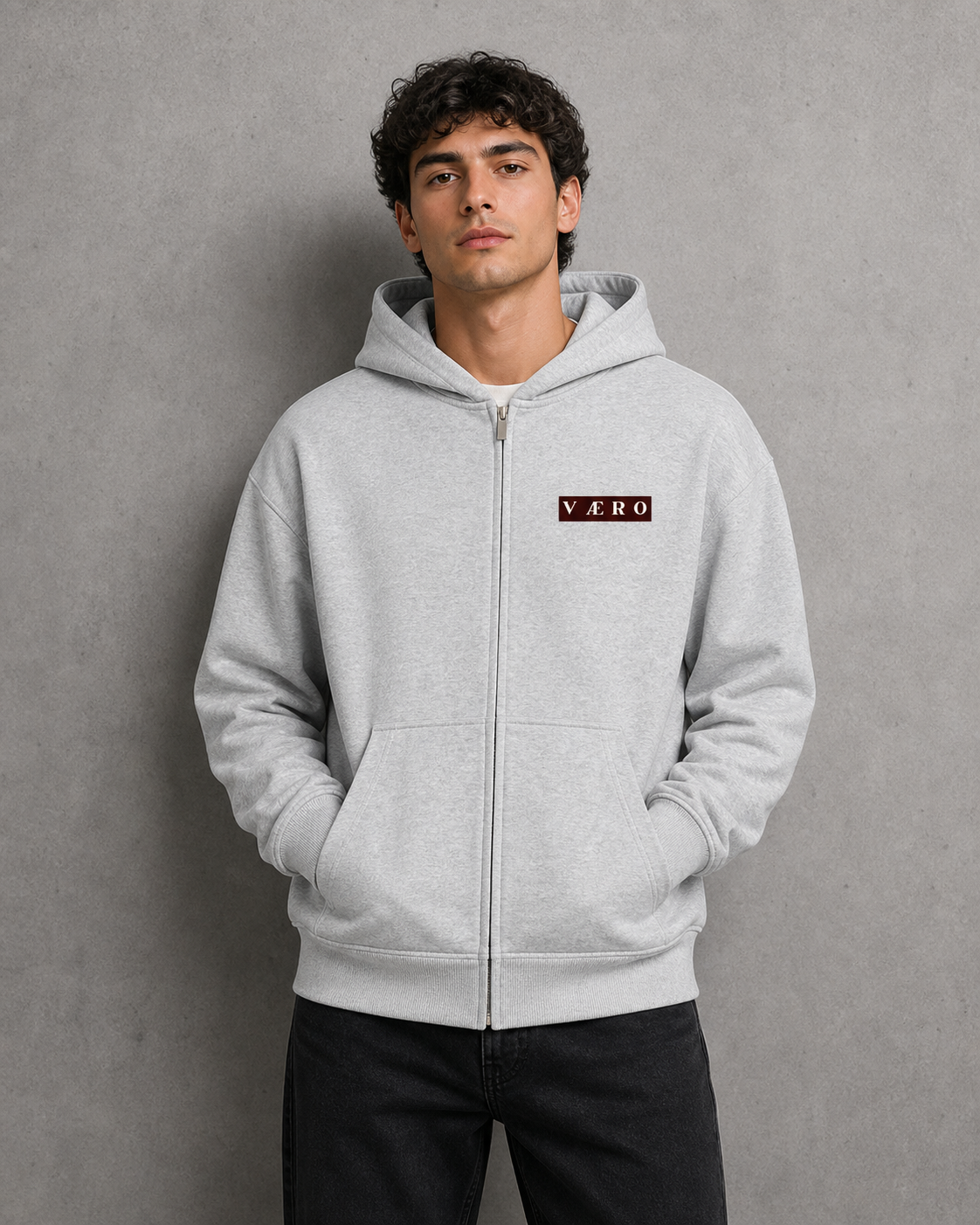 Man wearing a gray hoodie with a logo on a gray background