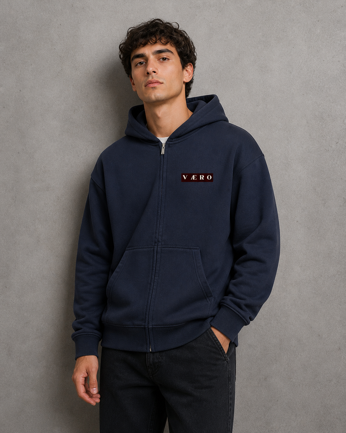 Man wearing a navy blue hoodie with a brand logo on a gray background