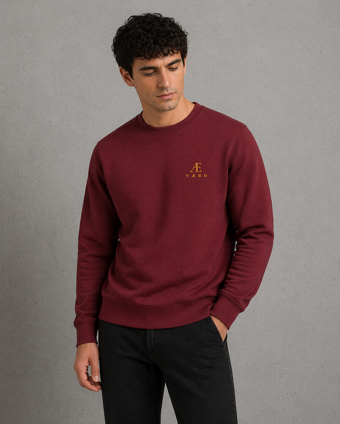 Man wearing a maroon sweatshirt with a logo on a gray background
