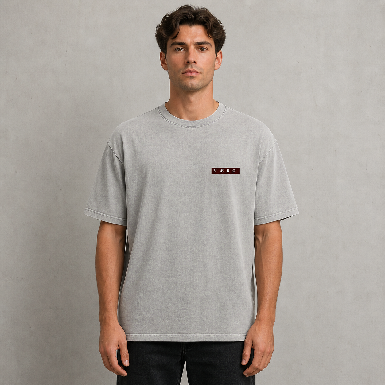 Man wearing a gray t-shirt with a small logo on a plain background
