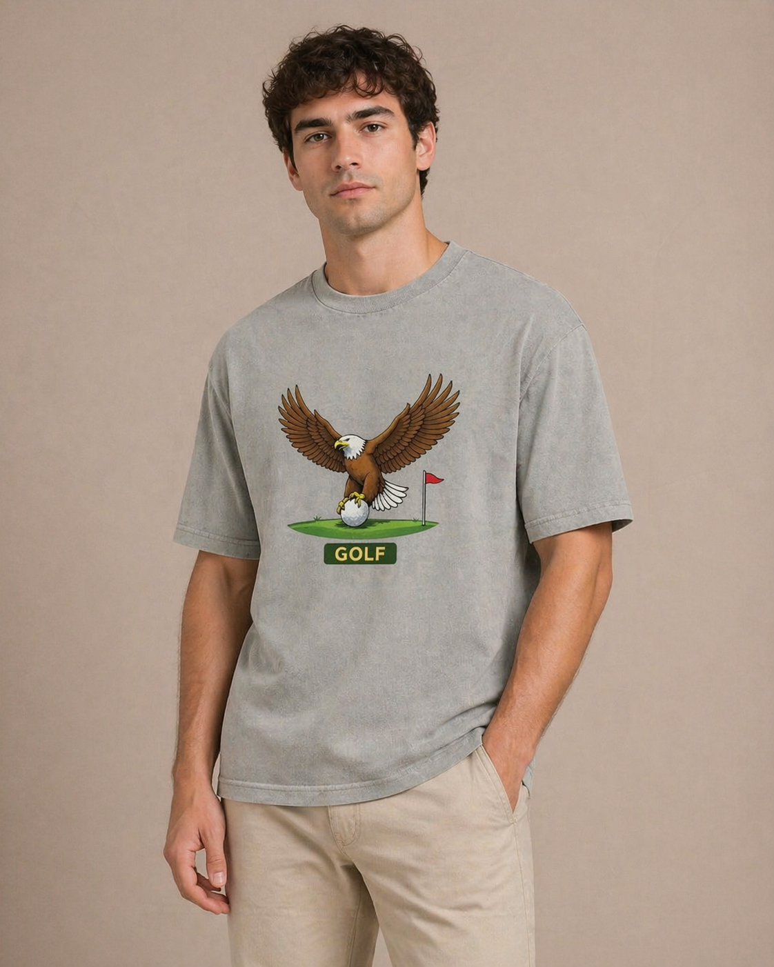 Man wearing a gray t-shirt with an eagle and golf ball graphic on a beige background