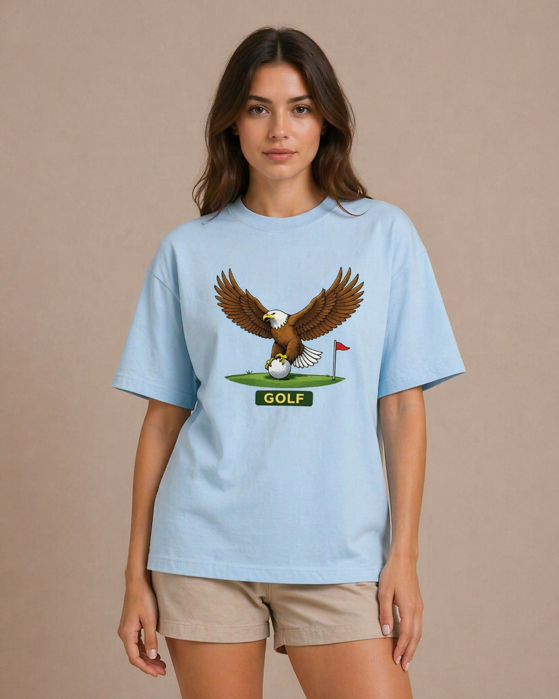 Woman wearing a light blue t-shirt with an eagle graphic and 'GOLF' text on a beige background