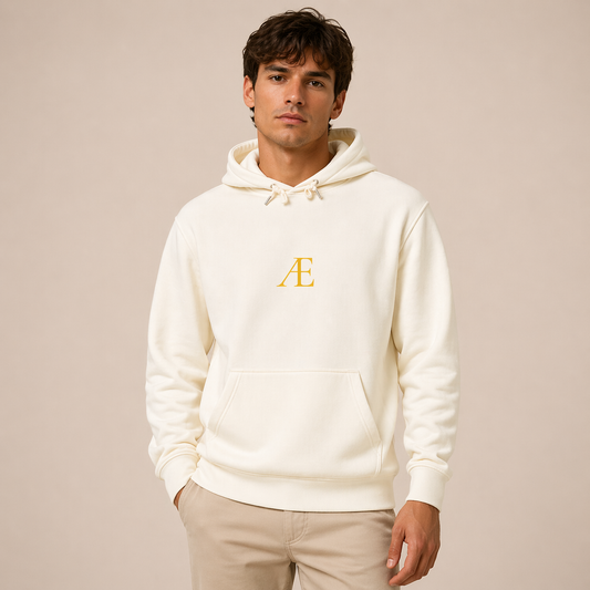 Man wearing a white hoodie with a gold logo on a beige background
