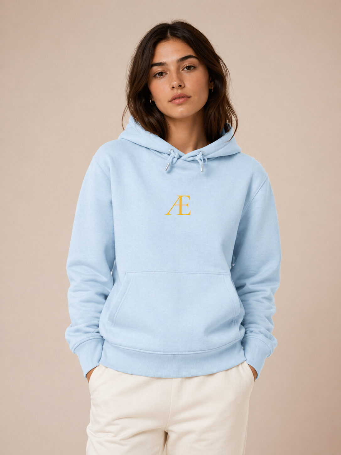Woman wearing a light blue hoodie with a logo on a beige background